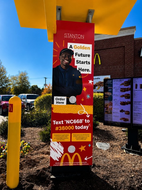 A Now Hiring wrap on a McDonald’s of Stanton drive-thru pillar