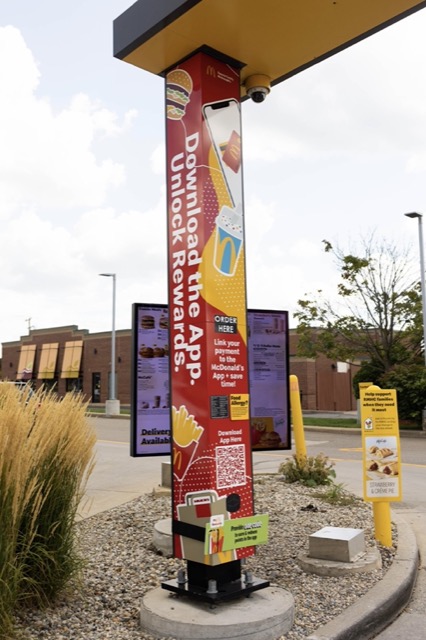 A drive-thru order point wrapped in Download the App artwork with a QR code