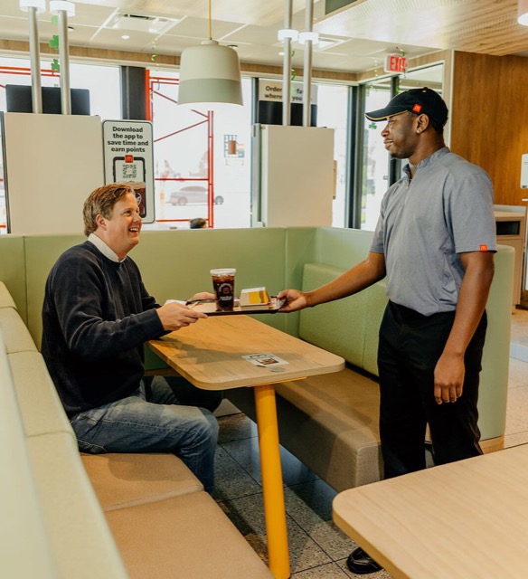 Taylor Buford, CEO of Sandlot + Co., receiving an order from a McDonald's crew member inside a restaurant