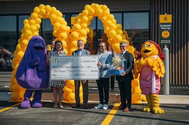 Owners, guests and mascots under a balloon arch at the Navarre grand opening